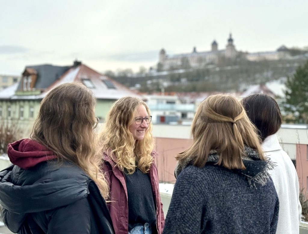 Junge Menschen stehen in Würzburg zusammen. Die Festung im Hintergrund.